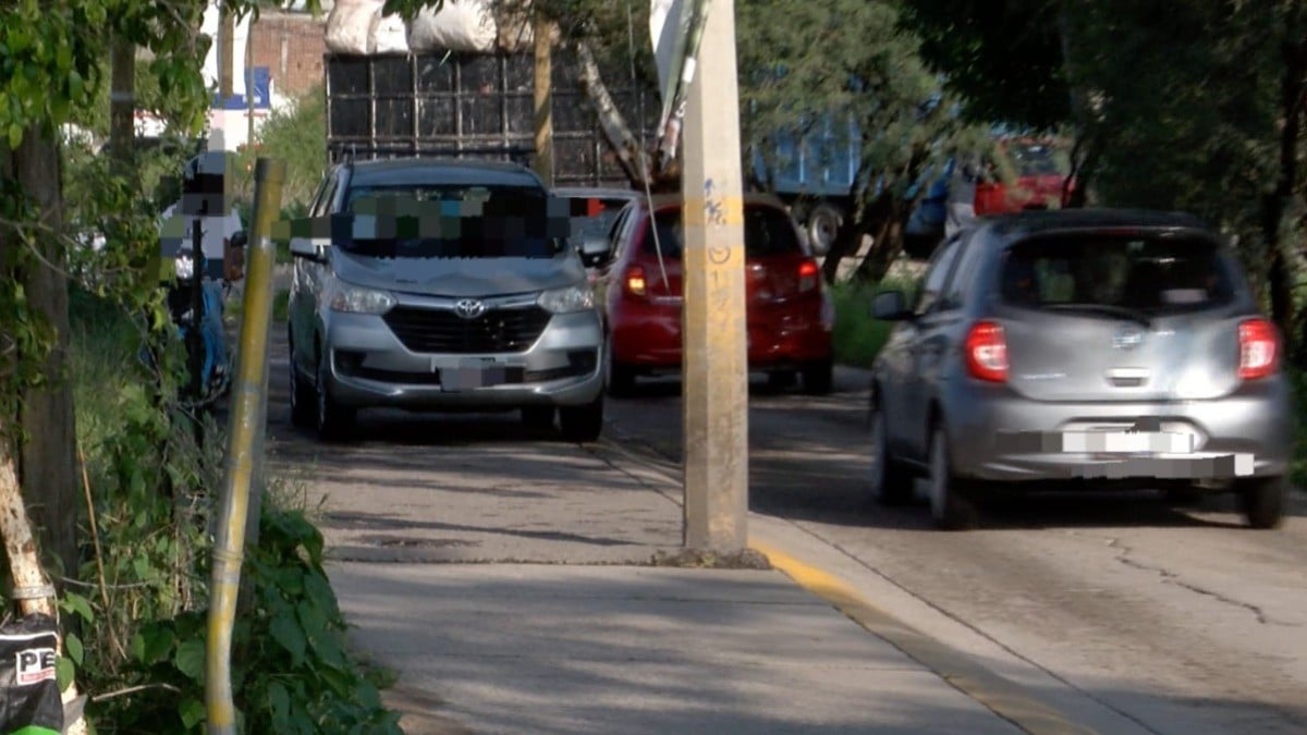 Carros tienen que subirse a la banqueta para pasar en calle de doble sentido en Las Camelinas