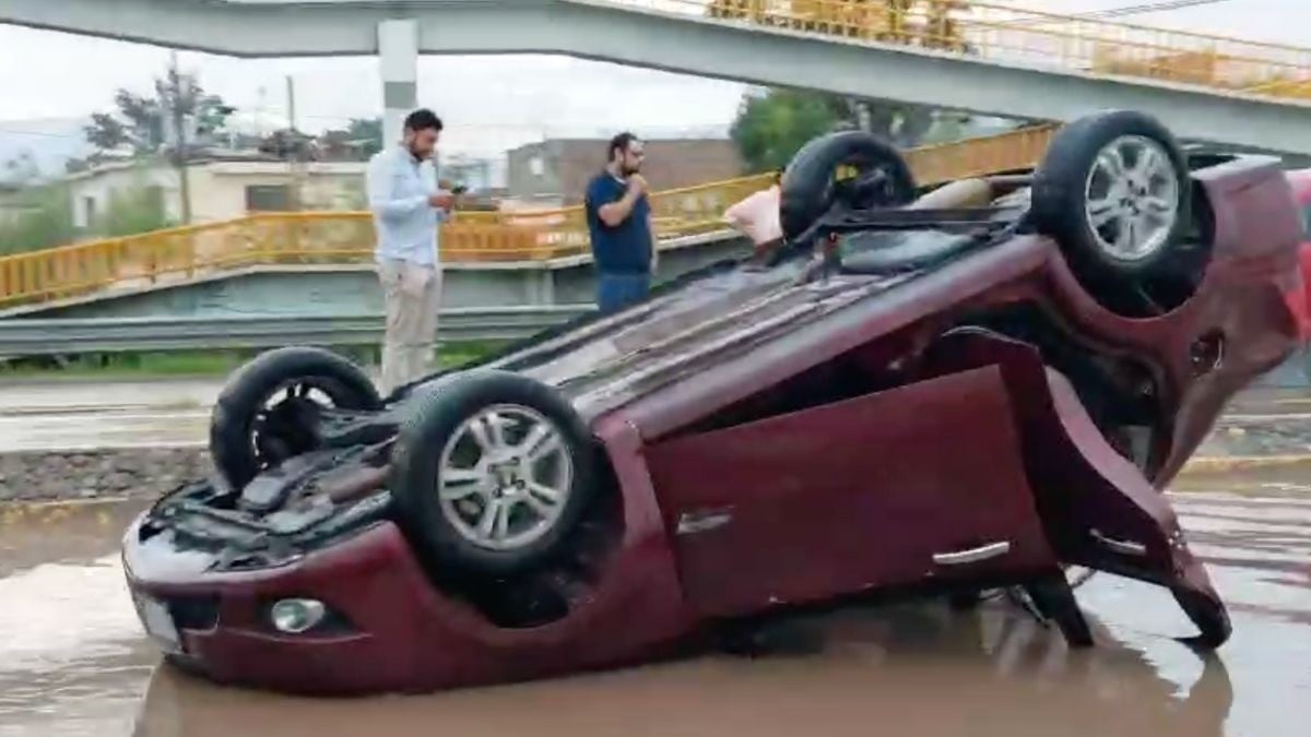 Carro pasa por charco, pega en el camellón y queda llantas arriba