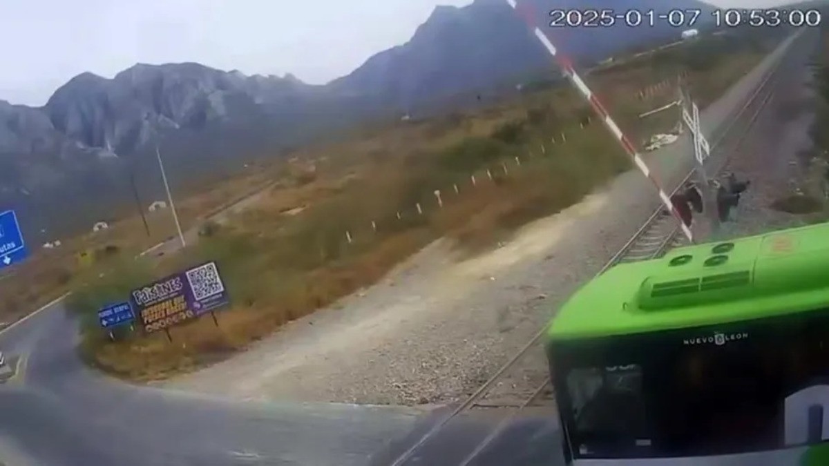 VIDEO Chofer de camión de pasajeros intenta ganarle al tren pero lo impactan y vuelca