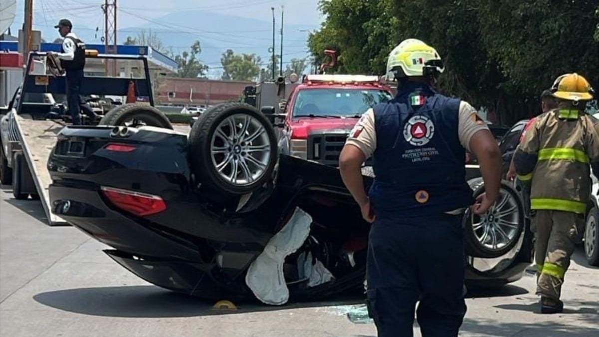 Conductor iba en un BMW cuando chocó y volcó, testigos le ayudan a salir del auto