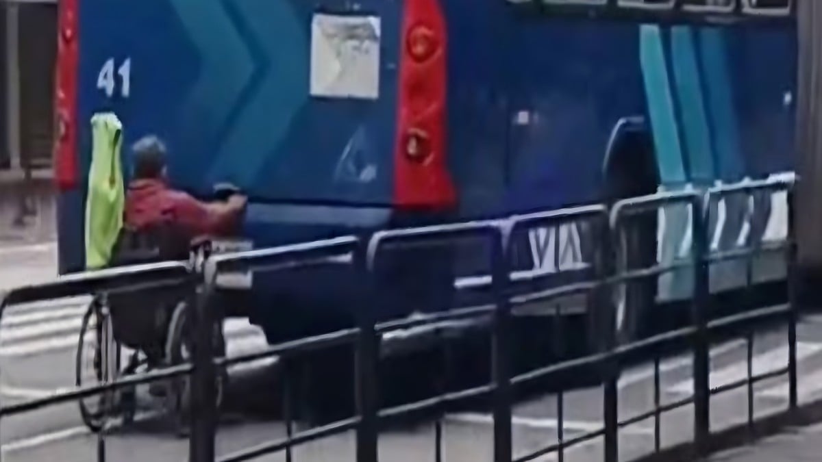 VIDEO Captan a hombre en silla de ruedas agarrado a la parte trasera del transporte público